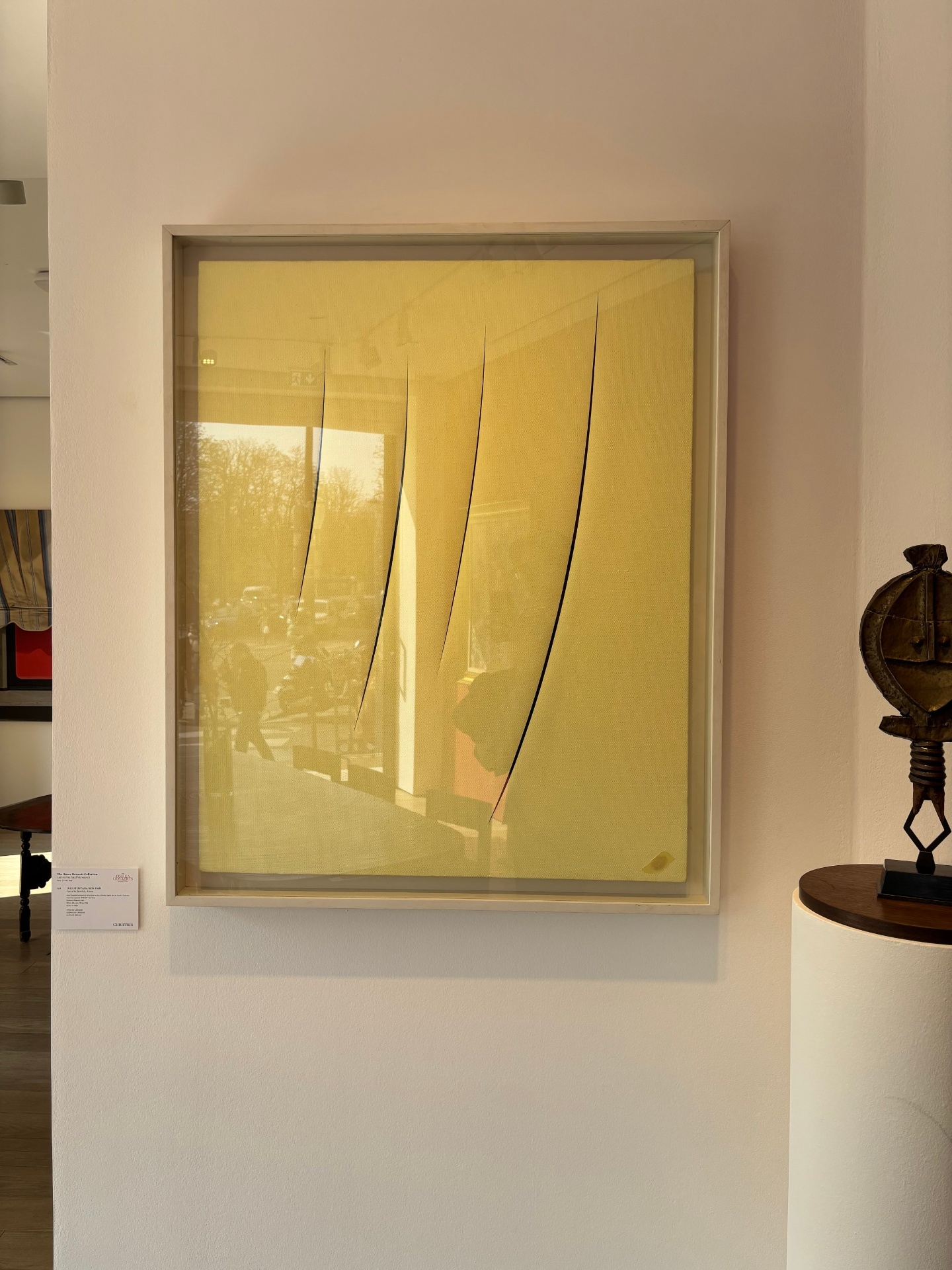Abstract artwork with yellow background and five black curved lines inside a white frame, displayed on a white wall.