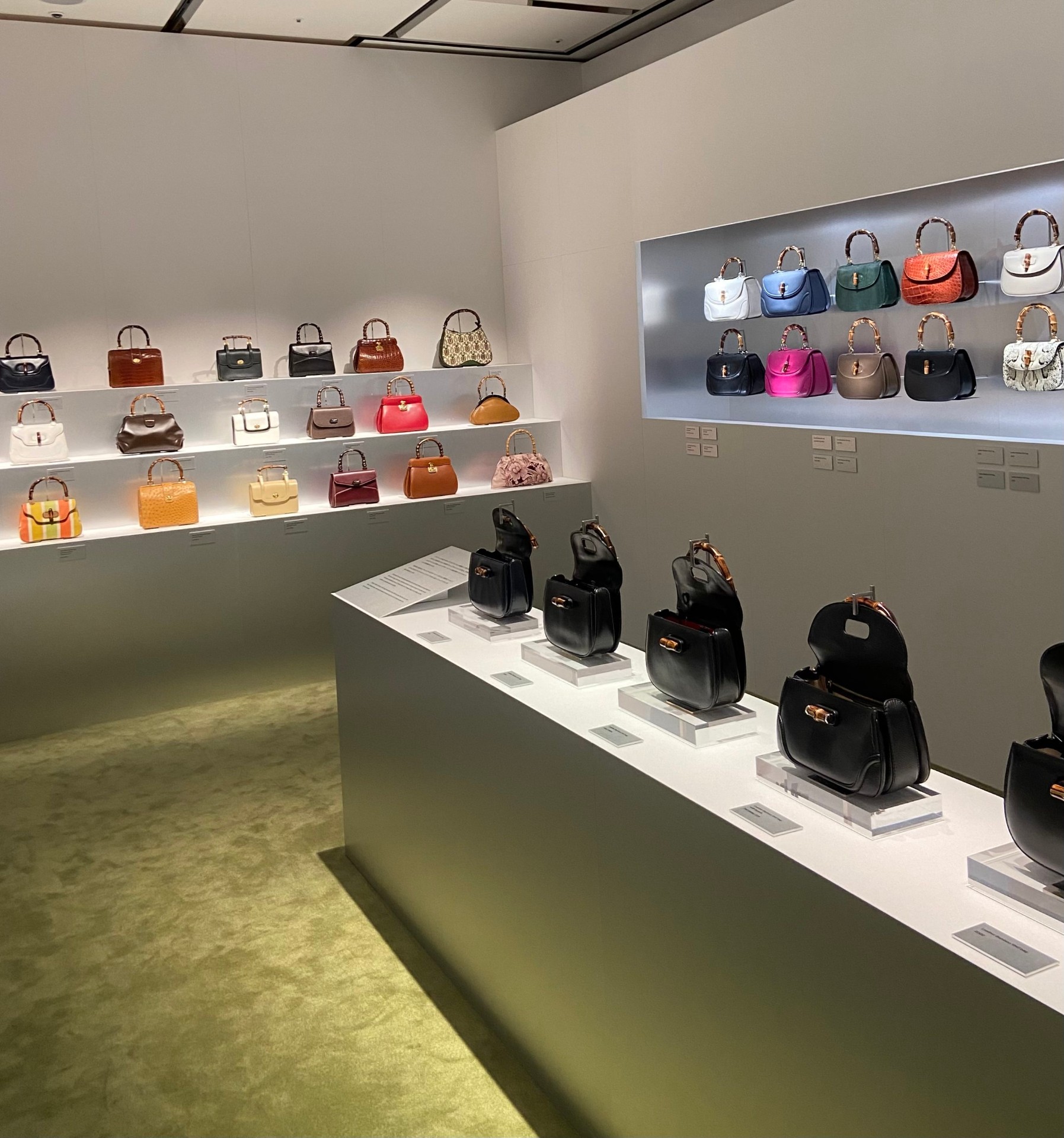 Display of various designer handbags in a modern store with shelves and spotlighting.