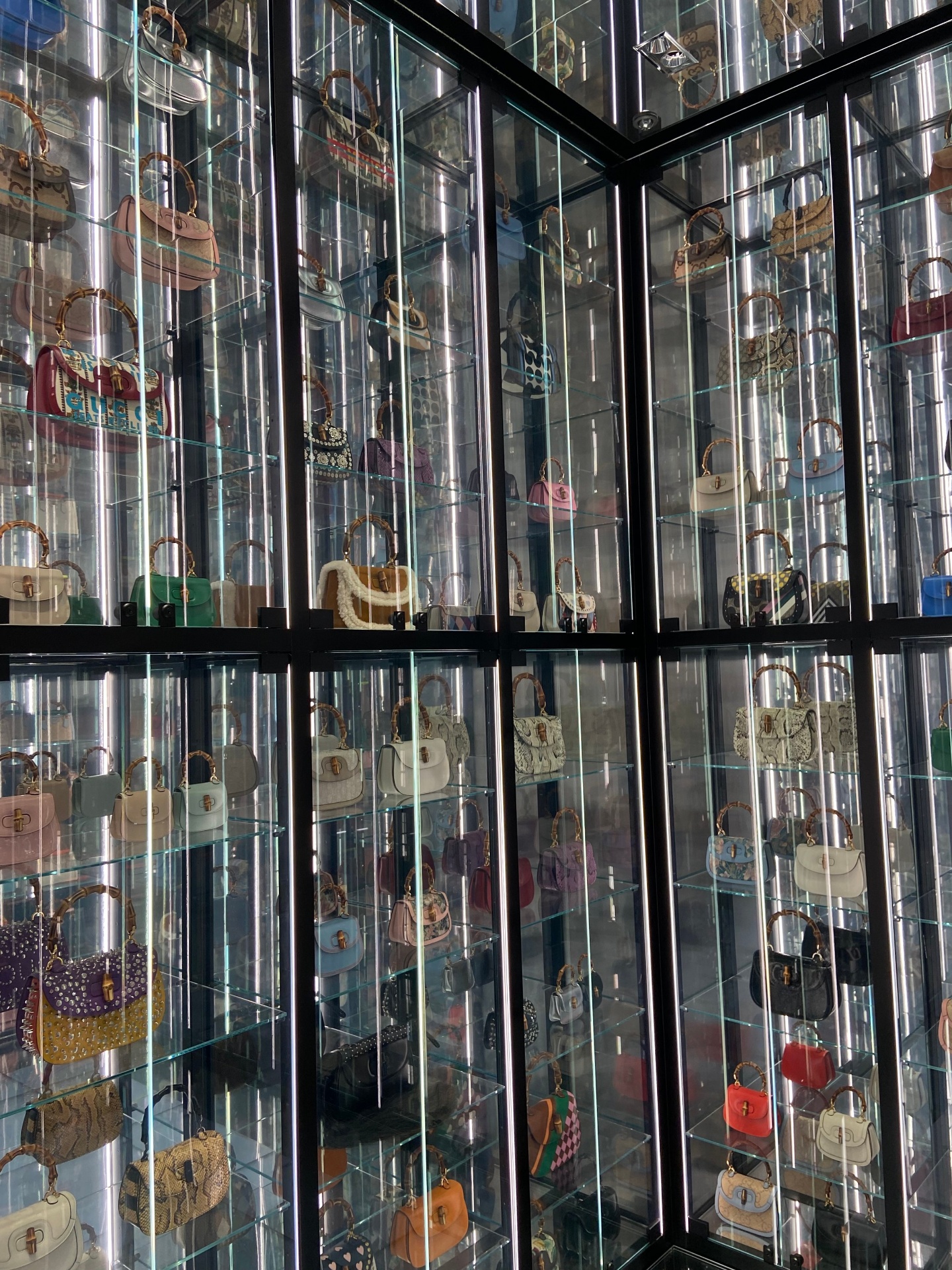 Display case with multiple shelves filled with various designer handbags in different colors and styles.