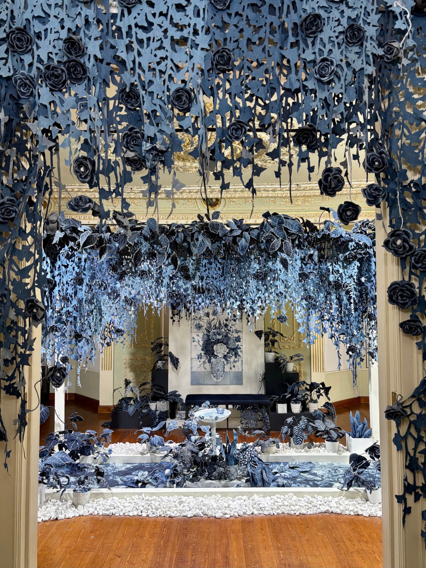 Foyer decorated with blue and white floral and leaf motifs, with hanging blue flowers and foliage, white pebbles on the floor, and a blue floral artwork on the wall.